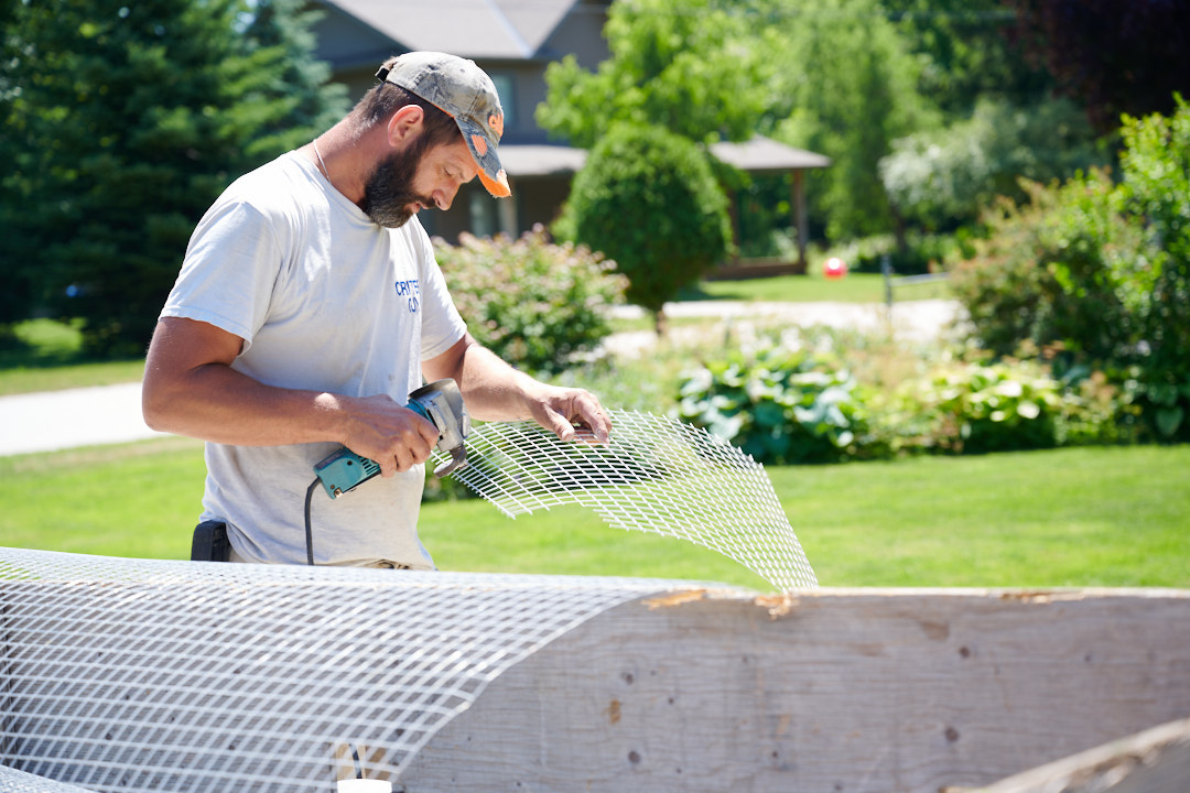The Critter Guy technician installing wildlife exclusion mesh